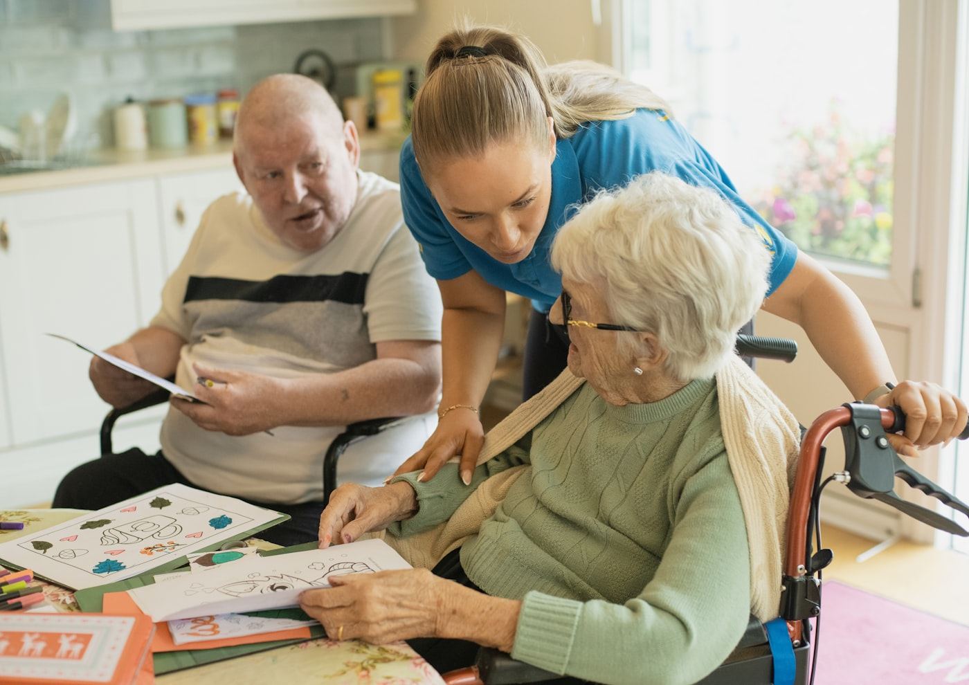 A caregiver assisting an older couple with an activity at home