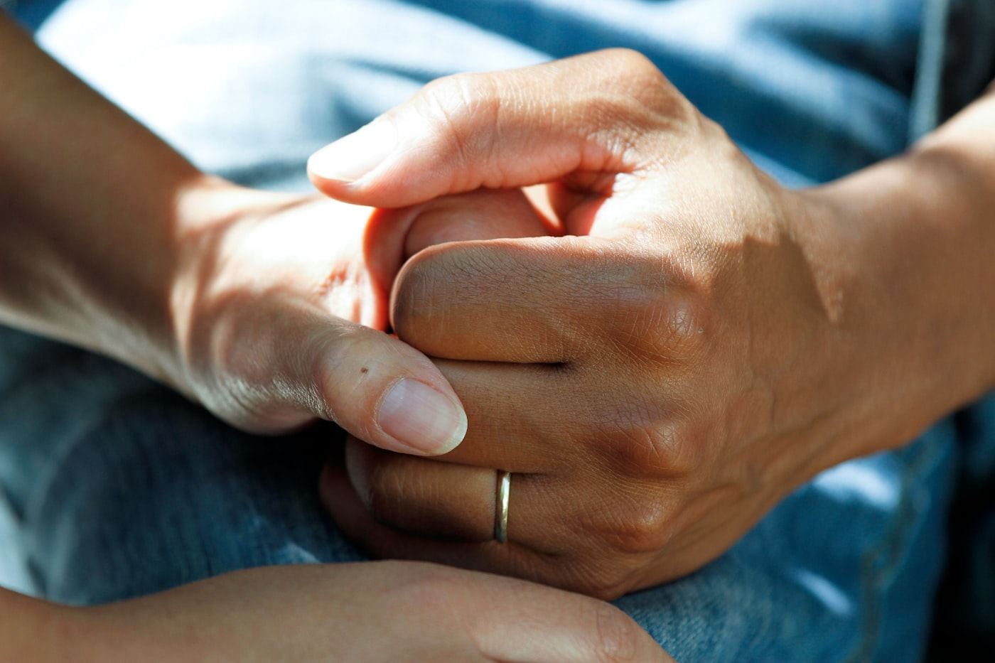 A caregiver gently holding the hand of an older client, offering comfort and reassurance